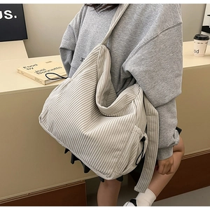 Detail view of large corduroy crossbody bag in beige hobo style on model