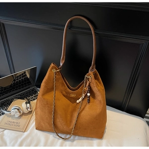 Close-up of brown suede tote bag with vintage metal chain and colorful beaded charm