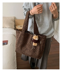 Detailed macro view of leopard print canvas tote bag with a cute bear plush keychain