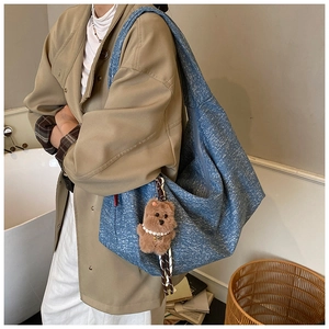 Detailed shot of large blue denim tote bag featuring a cute brown plush bear pendant