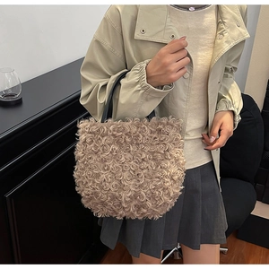 Detail of khaki plush bucket bag with curly faux fur texture and black leather handle