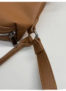 Detail of silver metal buckle and reinforced stitching on brown lychee leather bag