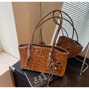 Détail du sac cabas léopard avec bandoulières et breloques décoratives en métal chic