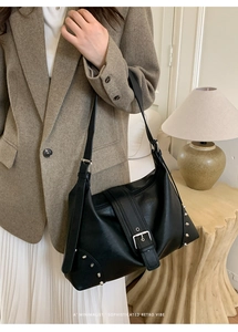 Detail view of black leather hobo bag with silver rivets and wide strap metal buckle