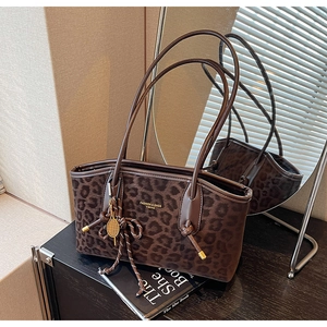 Détail du cabas léopard avec anses en cuir et breloque de raquette de tennis dorée