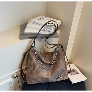 Detailed macro view of vintage brown leather tote bag with thick silver metal chain accessory