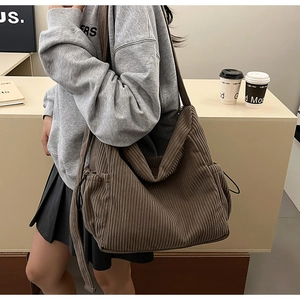 Detail of dark brown corduroy tote bag showing thick ribbed texture and side drawstring pocket