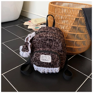 Detail of leopard print mini backpack with white lace edges and sweet bow decorations