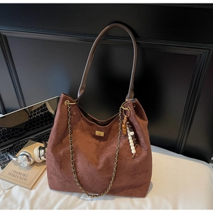 Brown suede shoulder bag with gold twist lock and chic beaded charm in office setting