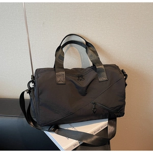 Détail d'un grand sac de voyage noir avec coutures géométriques et bandoulière réglable