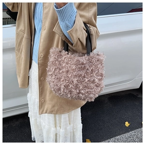 Dettaglio della trama in lana d'agnello riccia su una borsa a secchiello rosa antico