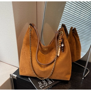 Macro detail of brown suede hobo bag with vintage metal lock and beaded charm