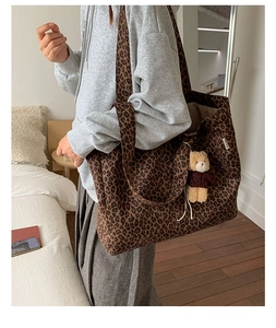Detail of a large leopard print canvas tote bag with a cute bear plush pendant in a room
