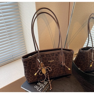 Détail du sac cabas vintage à motif léopard avec lettrage doré et pendentif décoratif