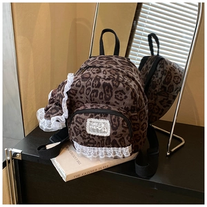 Detail of leopard print mini backpack with white lace trim and embroidered patch
