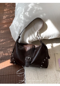 Detailed view of retro dark brown leather tote featuring buckle strap and silver rivet accents