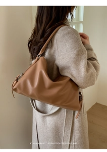 Brown litchi grain leather tote bag shown on model in a minimalist interior setting