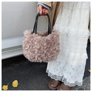 Dettaglio della borsa a secchiello in peluche rosa con manici in pelle nera a contrasto