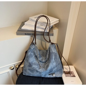 Detail of vintage blue denim tote bag with silver chain, heart charm and leather straps