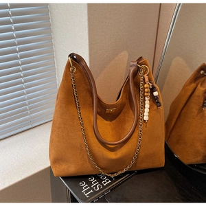 Close-up of brown suede hobo bag with gold chain strap and boho bead tassel detail