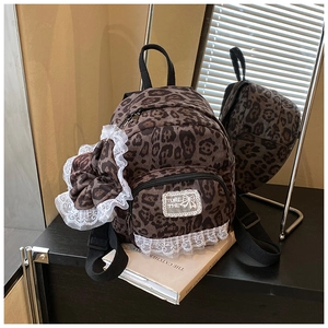 Close-up of leopard print backpack with white lace trim and large decorative bow detail