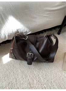 Close-up of vintage brown leather tote bag with silver rivets and metal buckle detail