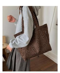 Detailed side view of large leopard print canvas tote bag on a model's shoulder