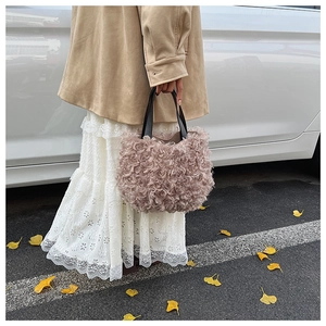 Foto street style di una borsa a secchiello in peluche rosa con manici in pelle nera