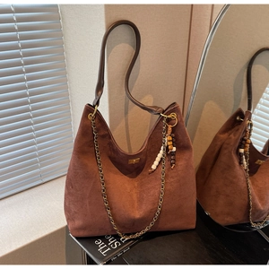 Detailed close-up of dark brown suede hobo bag with gold chain and beaded accessory