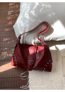 Close-up of wine red faux leather tote bag with silver rivets and metal buckle detail