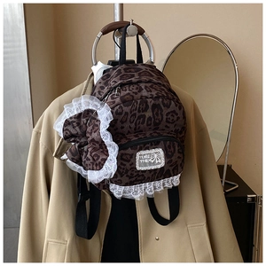 Detail of leopard print backpack with a large lace-edged bow and brand text on front pocket