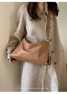 Detail of caramel lychee grain hobo bag worn with a beige tweed coat for a retro vibe