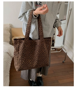 Close-up of leopard print canvas tote bag carried by a model in a cozy indoor setting