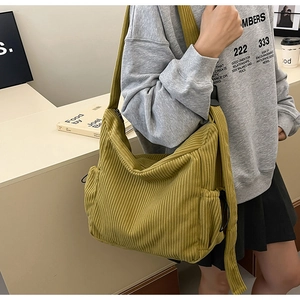 Detail of ginger yellow corduroy crossbody bag with drawstring side pockets and wide strap