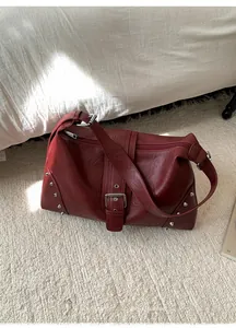 Detail view of dark red vintage tote bag featuring silver studs and buckle strap decor