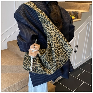 Detail of leopard print hobo bag with plush bear charm worn with a navy pinstripe blazer