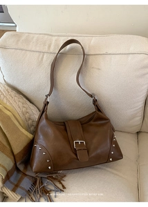 Close-up of caramel brown leather tote bag with silver rivets and metal buckle detail