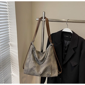 Detail view of vintage grey tote bag with bold silver chains and slim brown straps