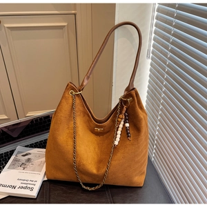 Detail of tan suede hobo bag with leather strap, metal chain, and wooden bead charm