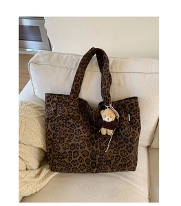 Detail of leopard print canvas tote bag featuring a cute plush bear charm accessory