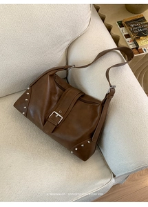 Detail view of the dark brown leather shoulder bag with silver rivet studs and buckle