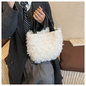 Detail of white curly plush bucket bag with contrasting black leather handles