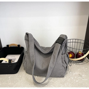 Detail of grey corduroy tote bag featuring adjustable strap and side drawstring pocket