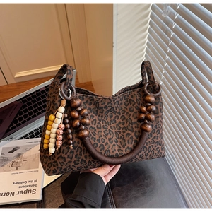 Detail der Leopard-Tasche mit einzigartigen Holzperlengriffen und farbigem Anhänger