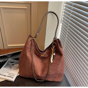 Detail of warm brown suede shoulder bag with chain strap and vintage beaded charms