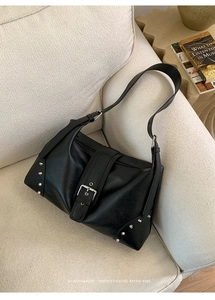 Detail shot of vintage punk black leather tote with silver studs and metal buckle closure