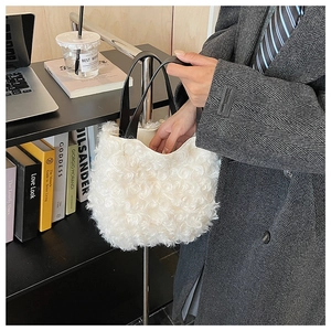 Detail of white plush bucket bag with spiral faux fur texture and black leather handles