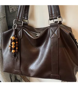 Détail du grand sac cabas marron foncé, texture cuir lisse et breloque en perles de bois