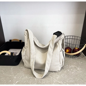 Detail of ivory corduroy crossbody hobo bag showing vertical ribbed texture and side pocket