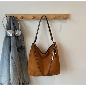 Detailed shot of brown suede tote bag with leather strap and chain detail on a hanger